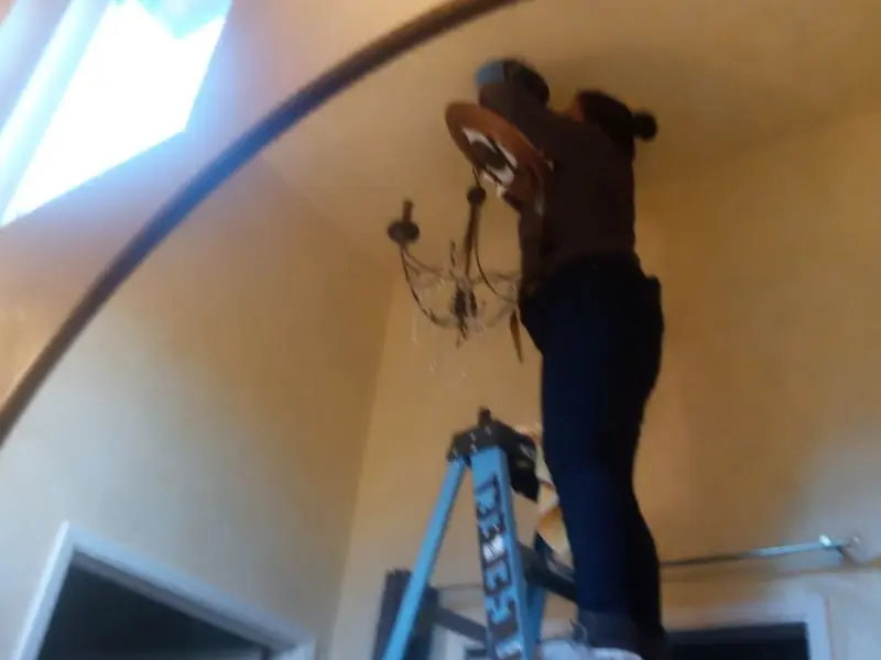 Electrician installing a chandelier in a Amelia residence